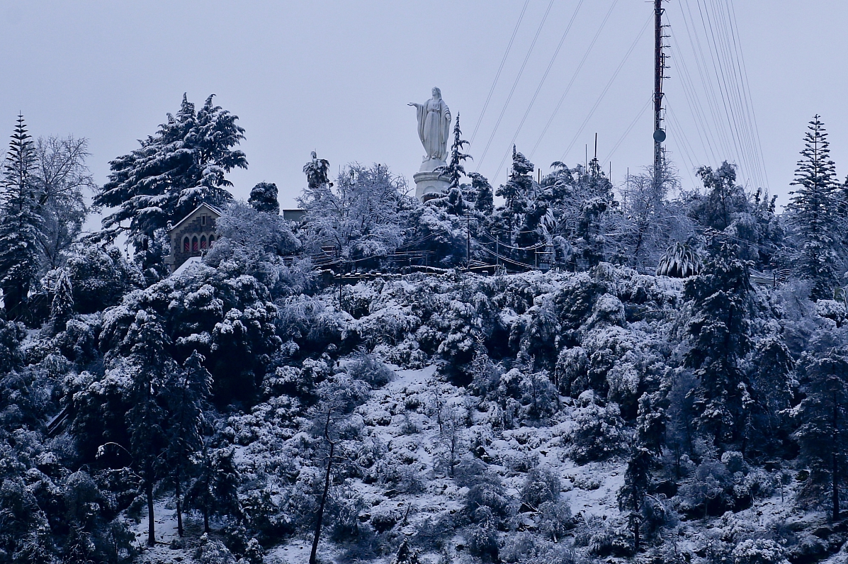 A statue of the Blessed Virgin Mary stands on the summit of the snow-covered San Cristobal Hill, in...