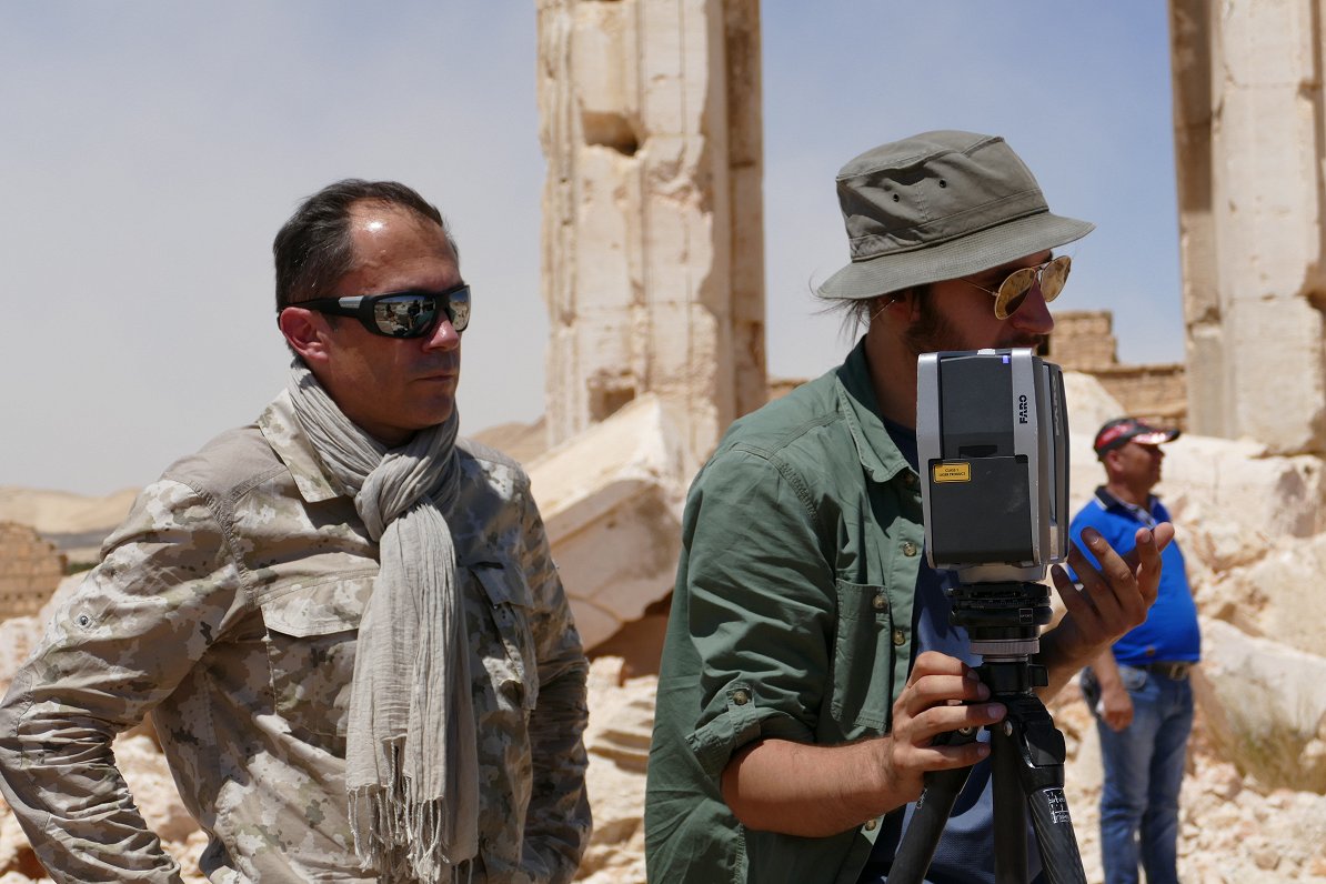 Attēlā Bruno Delands ar kolēģi Palmīras pilsētā Sīrijā