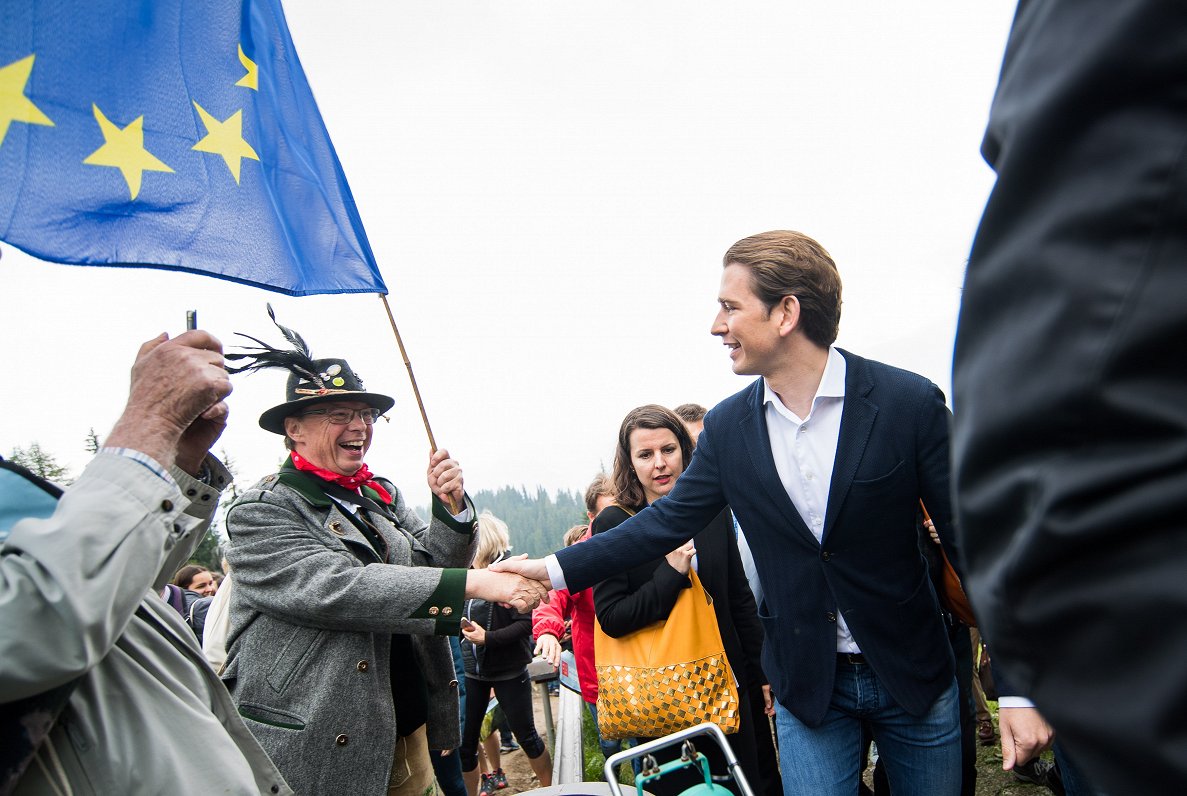 Austrijas premjers Sebastjans Kurcs sasveicinās ar kādu austrieti ar ES karogu rokās