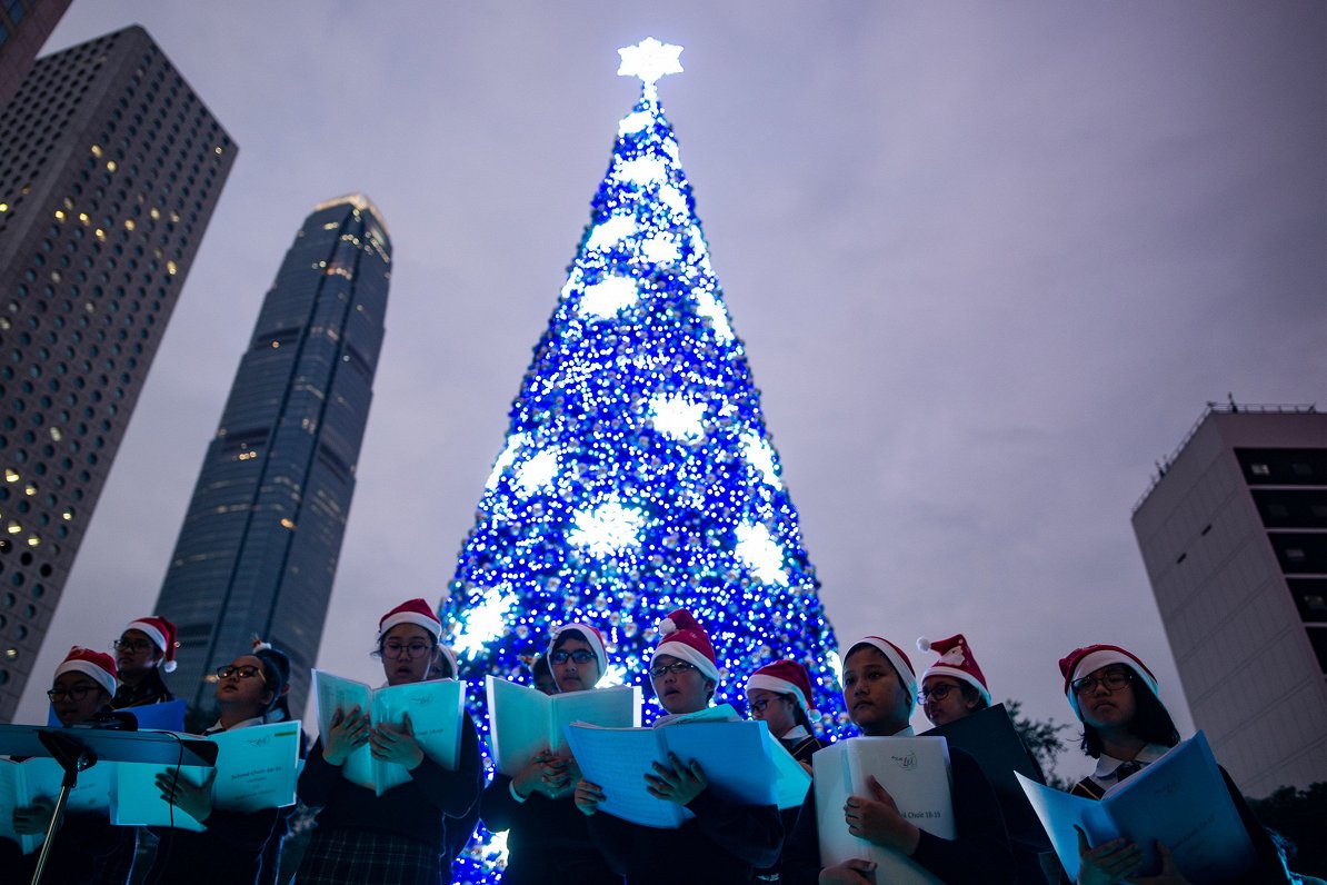 TOPSHOT - A primary school choir sings Christmas carols beneath a Christmas tree in the Central dist...