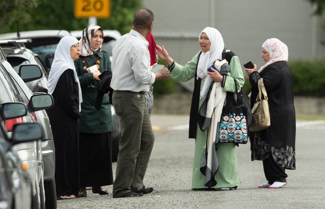 epa07438399 Shocked family members stand outside the mosque following a shooting resulting in multip...