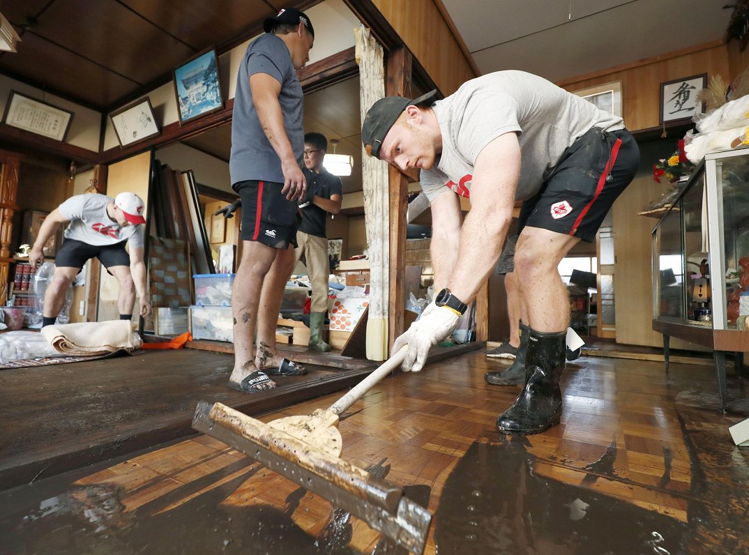 Kanādas regbists Pīters Nelsons palīdz tīrīt Kamaisi pilsētā taifūnā cietušu māju