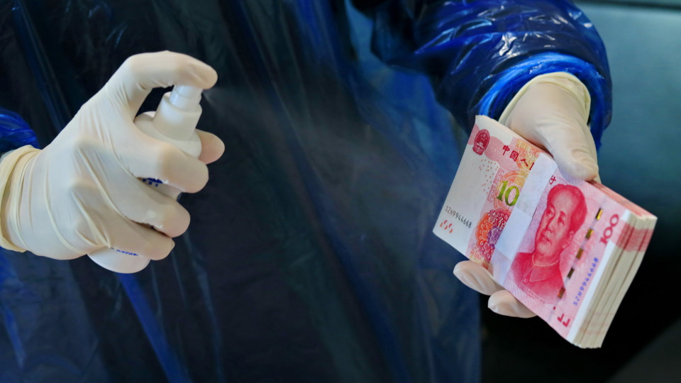Служащий китайского банка дезинфицирует банкноты.