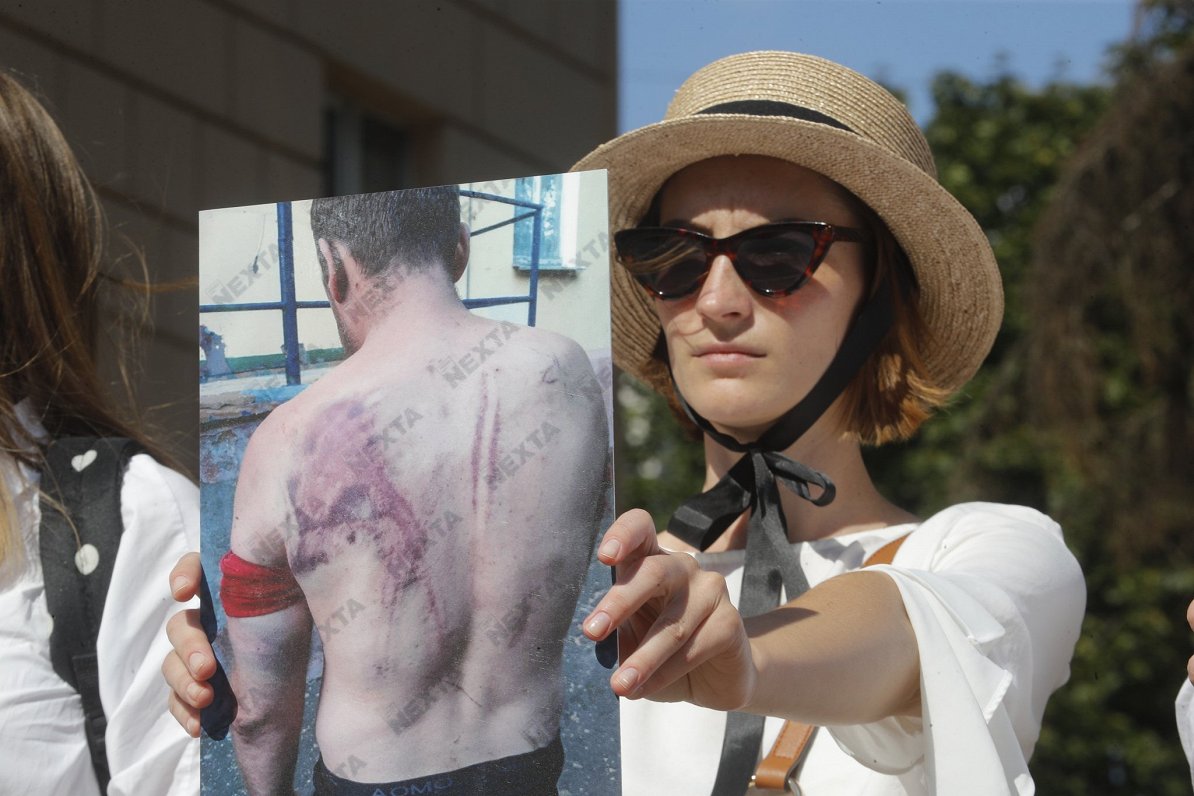 Attēlā: Sieviete tur rokās fotogrāfiju ar protestētāju, kurš pret Lukašenko vērstā mītiņa laikā ciet...
