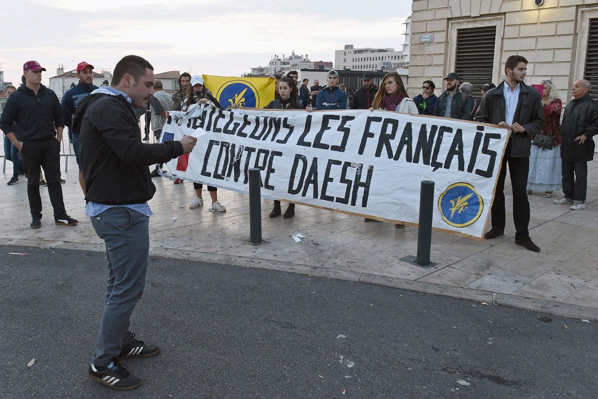 Protestētāji Parīzē ar plakātu &quot;Pasargājiet frančus no &quot;Daīšs&quot;&quot;