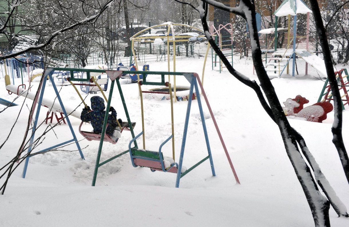 Bērns rotaļu laukumā ziemā.
