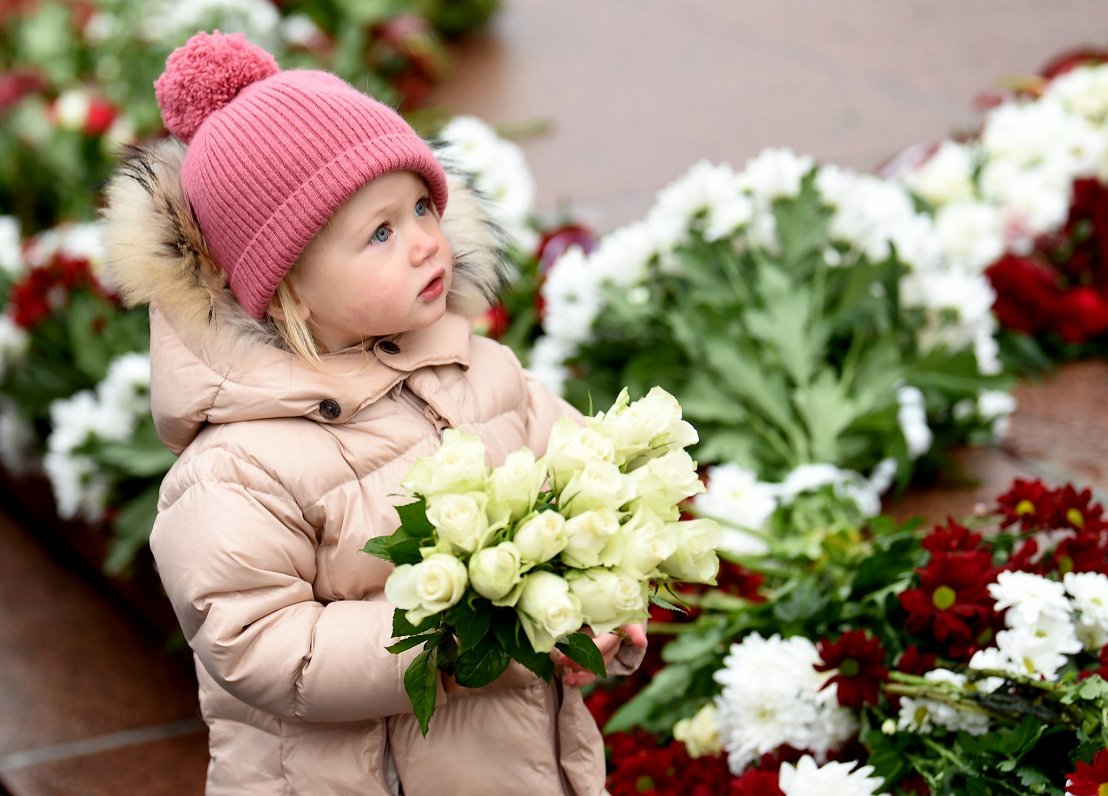 Meitene ar ziediem Latvijas proklamēšanas gadadienā pie Brīvības pieminekļa.