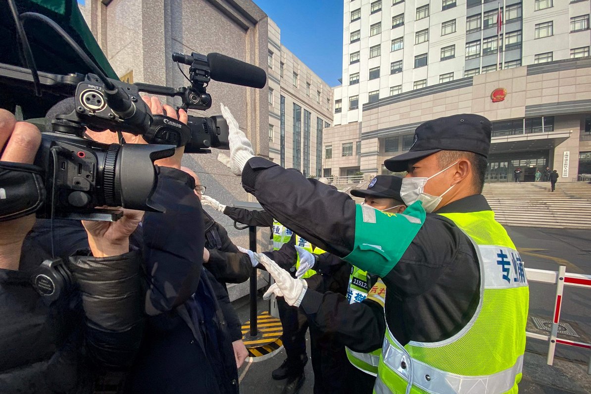 Policists Ķīnā aizsedz kameru pie tiesas ēkas, kur tiesā žurnālisti  Džanu Džaņu (28.12.2020)