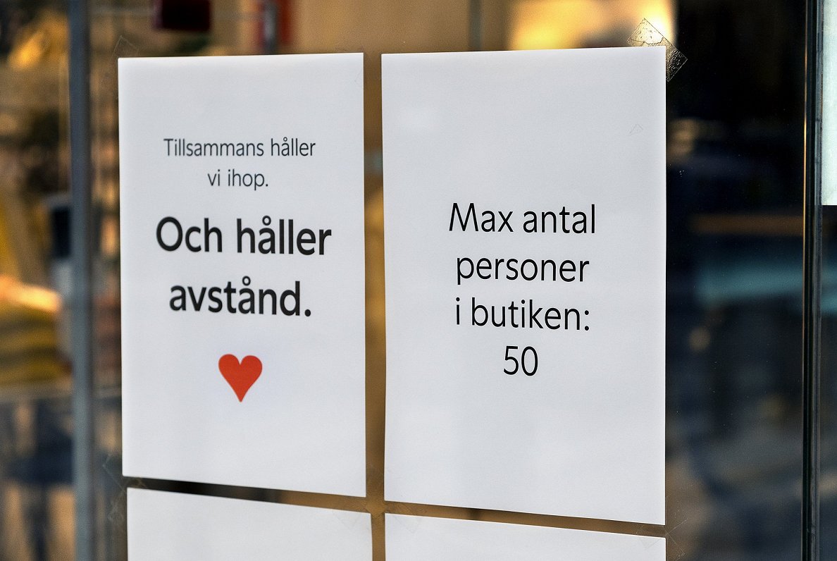 Zviedrijā norādes uz veikala durvīm, ka jāievēro distance (pa kreisi) un ka veikalā nevar būt vairāk...