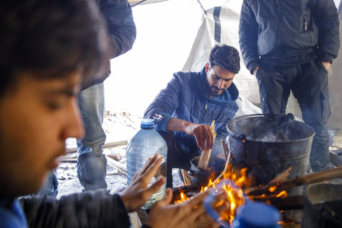 Migranti sildās pie ugunskura Bosnijā un Hercogovinā 2021. gada janvārī