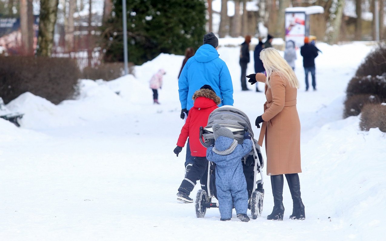Ģimene ar bērniem bauda ziemas pastaigu