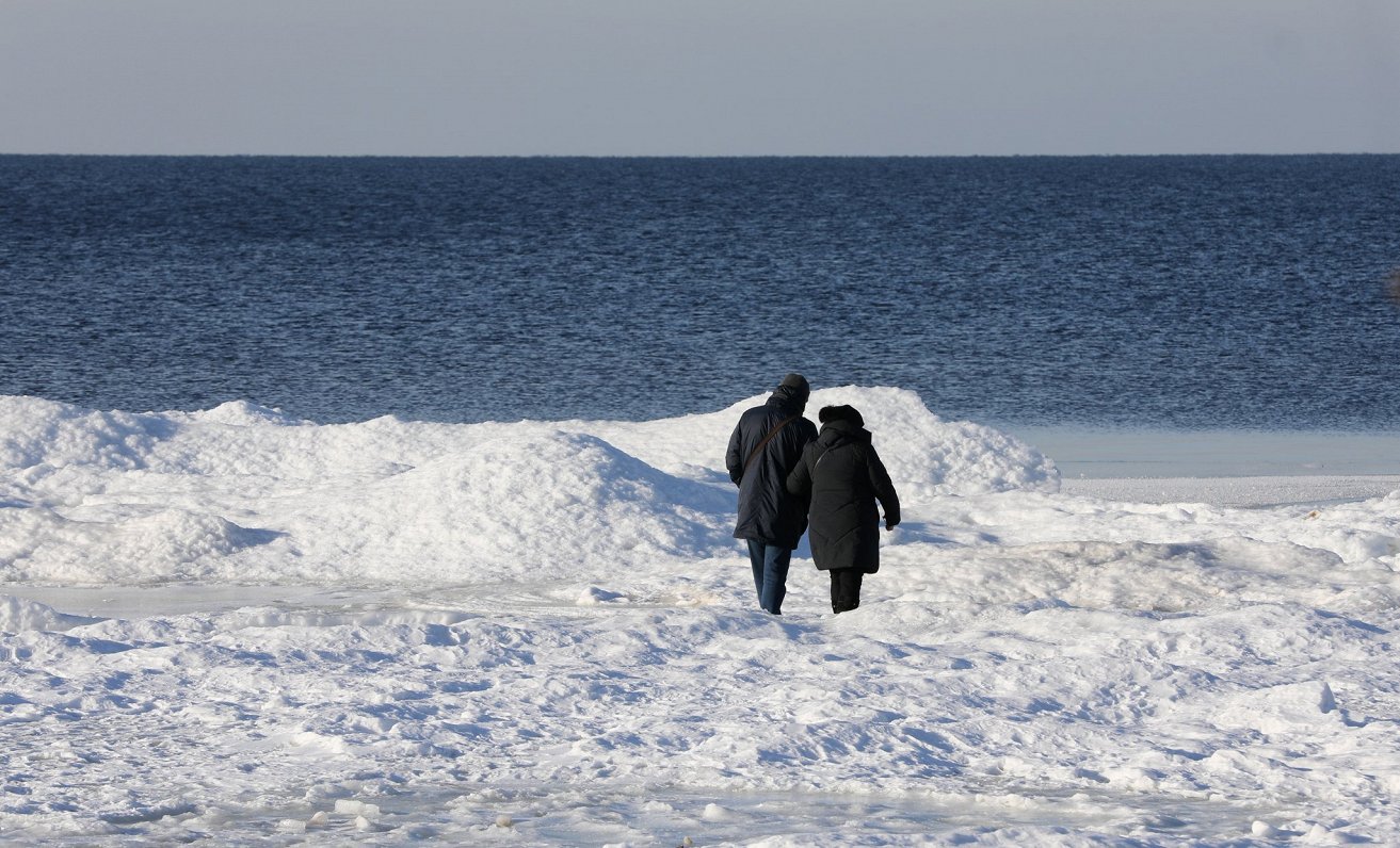 Cilvēki pastaigā Carnikavas pludmalē ziemā.