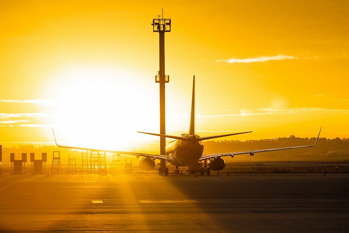 Lidmašīna uz lidostas skrejceļa saulrietā. Attēls ilustratīvs.