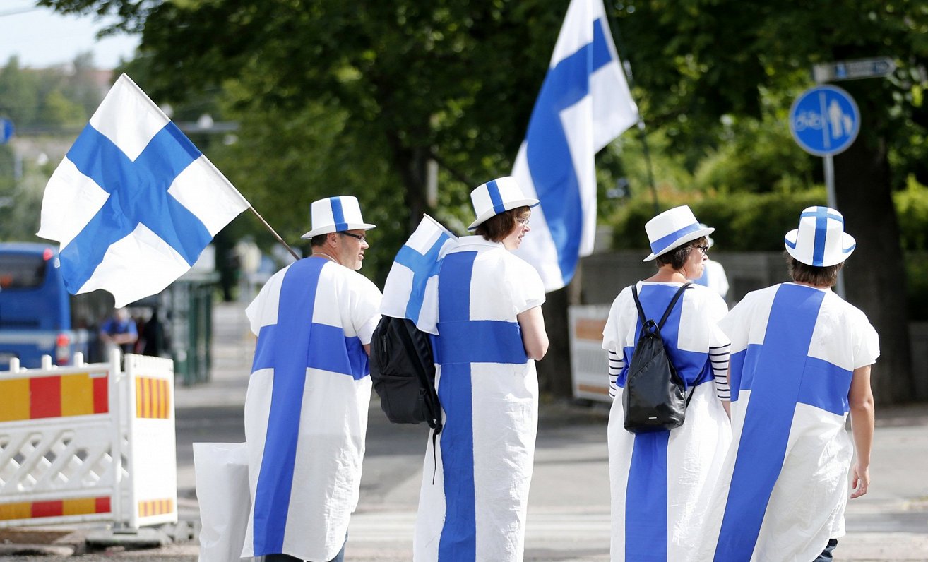 Cilvēki ar karogiem un ģērbti Somijas karoga krāsās. Attēls ilustratīvs.