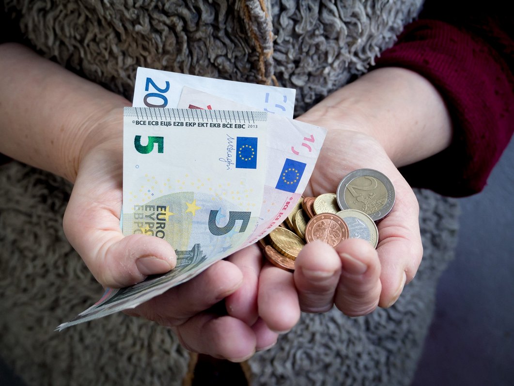 Seniors ar eiro naudas banknotēm un monētām
