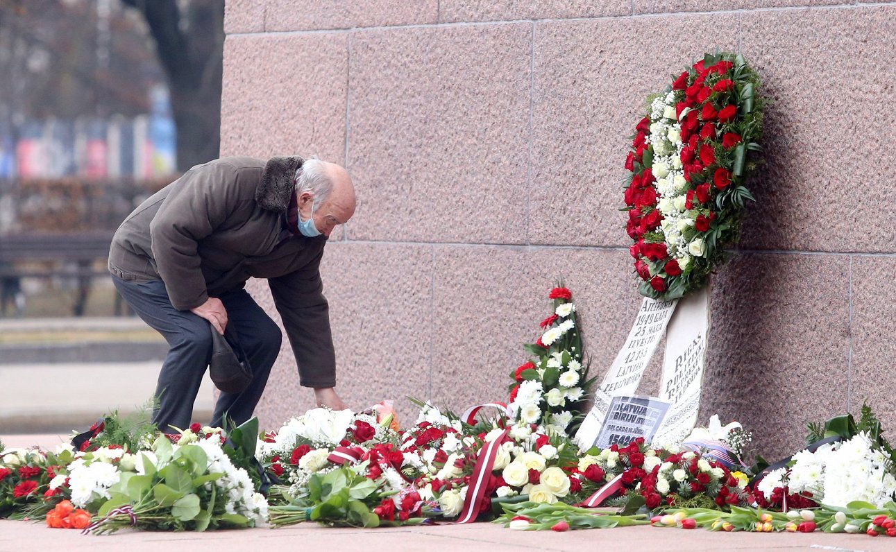 Komunistiskā genocīda upuru piemiņas dienā vīrietis noliek ziedus pie Brīvības pieminekļa.