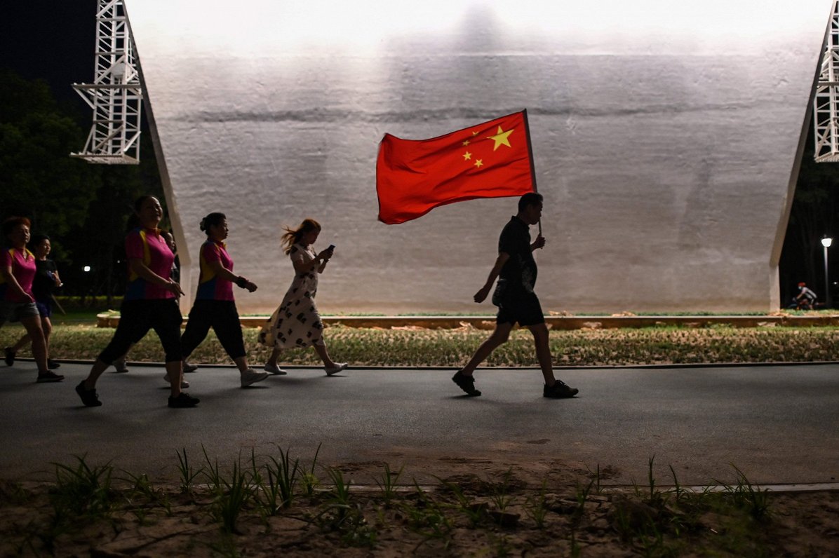Cilvēks ar Ķīnas karogu rokās. Attēls ilustratīvs.