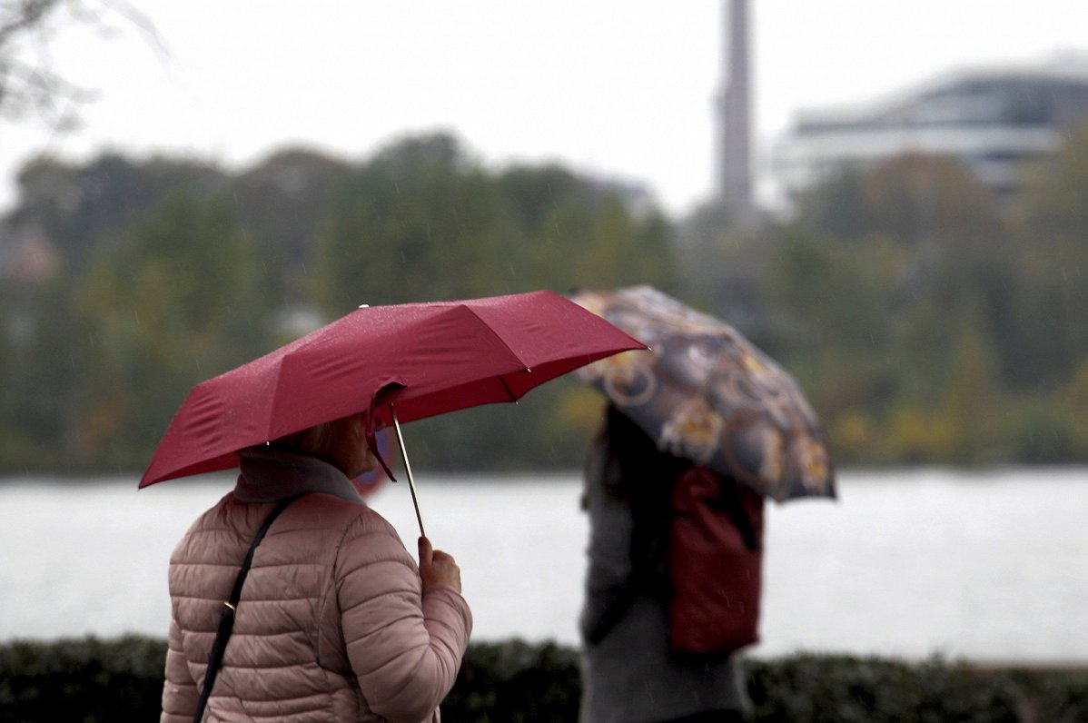 Cilvēki ar lietussargiem Rīgas parkā. Attēls ilustratīvs.