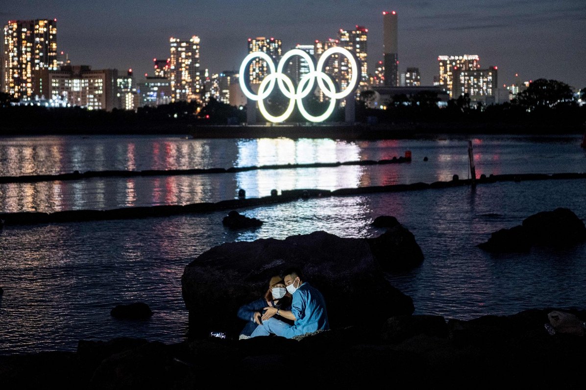 Japāņu pārītis uz Tokijas olimpisko apļu fona