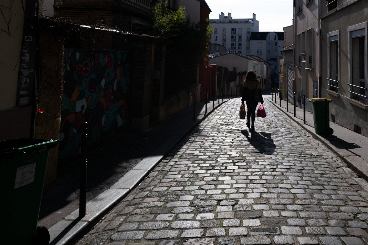 Sieviete ar iepirkumu maisiņiem Parīzē, Francijā. 2021. gada pavasaris.