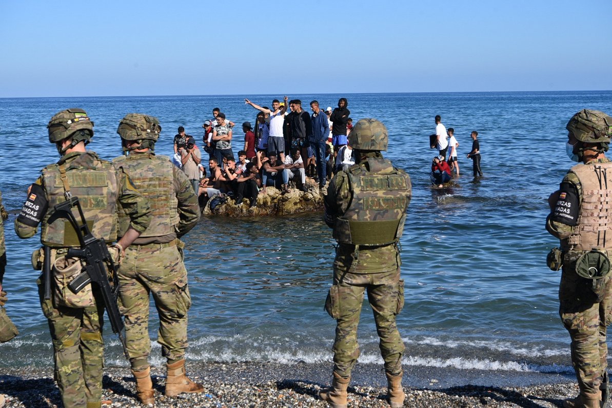 Spānijas armijas karavīri novēro migrantus, kas ieradušies Seutā