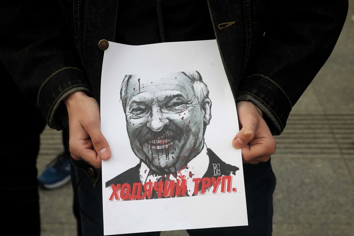 Protesta akcijā Varšavā plakāts ar Lukašenko attēlu un saukli &quot;Staigājošs līķis&quot;