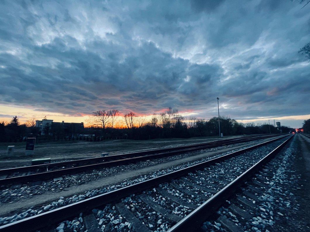 Dzelzceļa sliedes uz saulrieta debesu fona