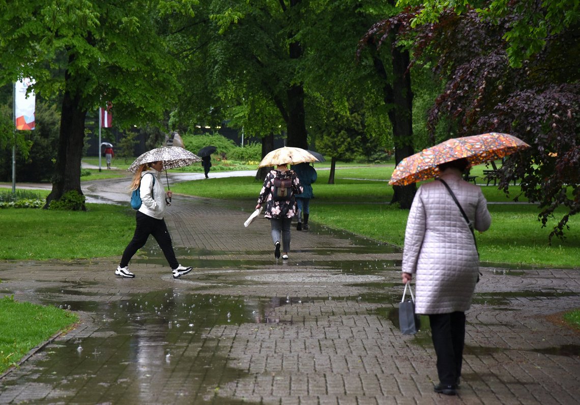 Cilvēki lietussargos un nelabvēlīgi meteoroloģiski laikapstākļi pilsētā. Attēls ilustratīvs.