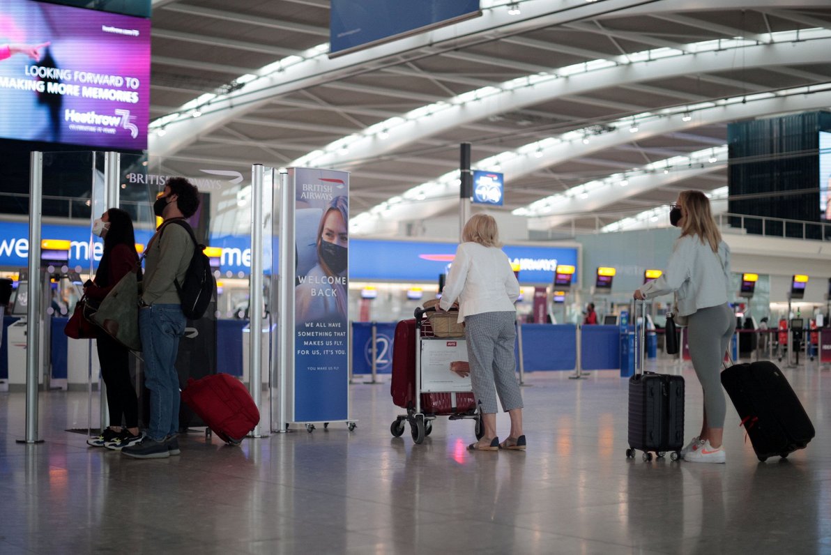 Cilvēki ar ceļojumu koferiem lidostā Covid-19 ierobežojumu apstākļos. Hītrovas lidosta, Londona, Lie...