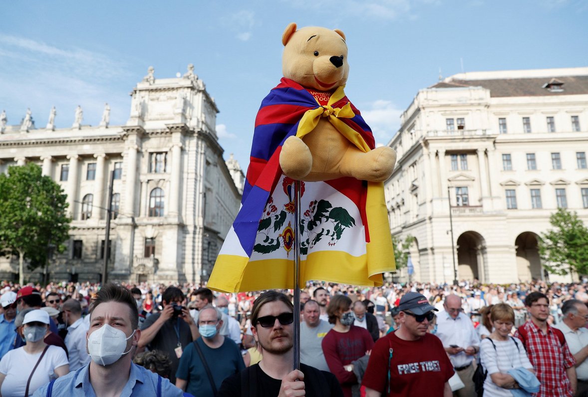 Protesta akcijas dalībnieki ar rotaļu lāci, kas ietinies Tibetas karogā