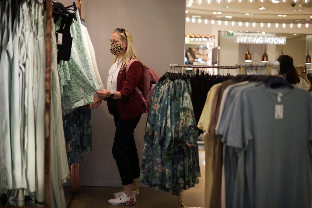 Sieviete izvēlas drēbes apģērbu veikalā. Attēls ilustratīvs