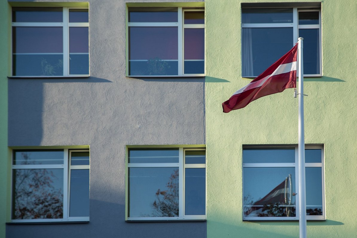 Valsts karogs pie vidusskolas ēkas korpusa.