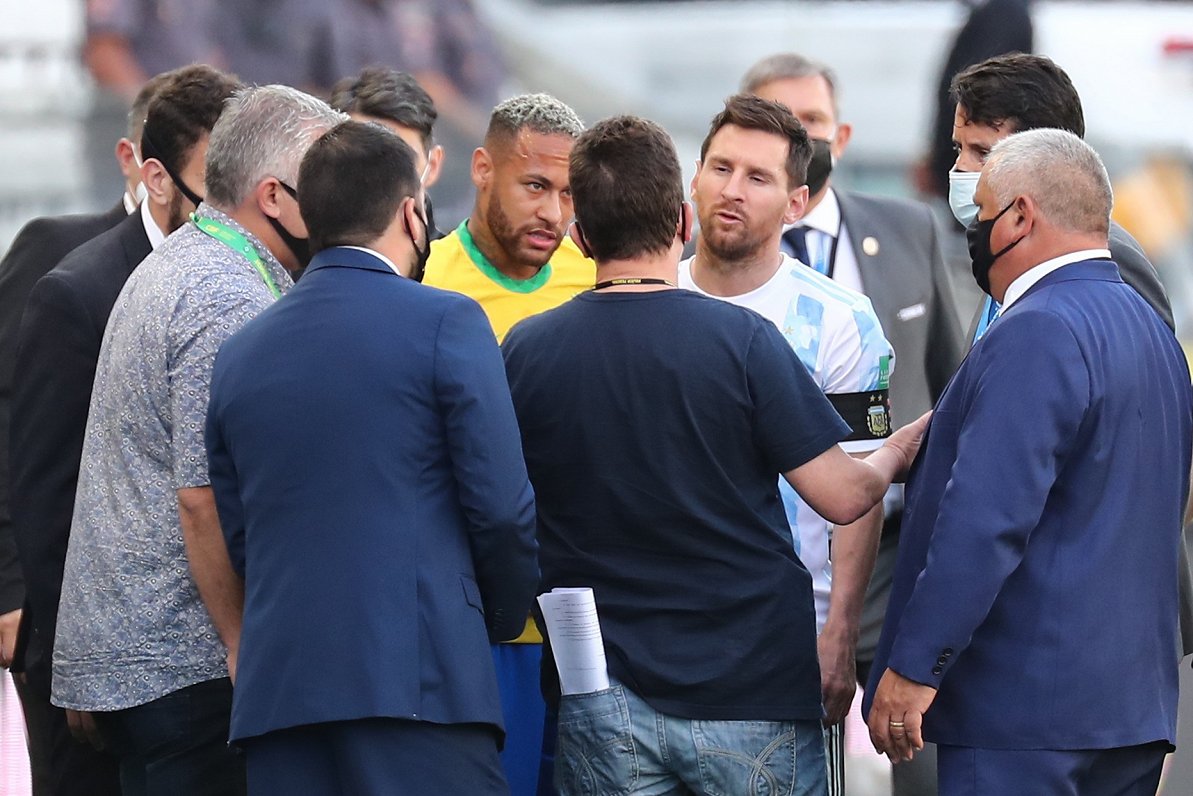 Brazīlijas futbolists Neimars (pa kreisi) un argentīnietis Lionels Mesi runā ar veselības uzraugiem