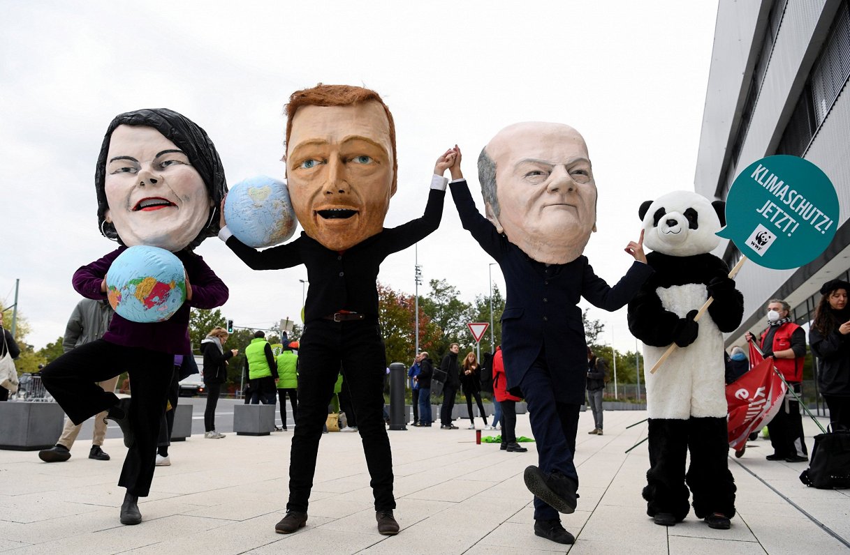 Vides aizsardzības aktīvisti, tērpušies koalīciju veidojošo partiju līderu maskās, pieprasa efektīvā...