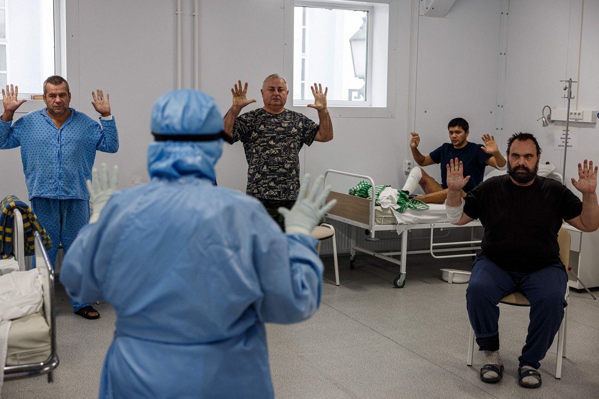 Врач в российской больнице показывает ковид-пациентам упражнения для нормализации дыхания.