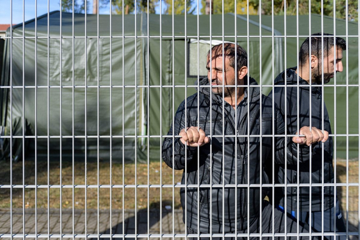 Irākiešu bēgļi pie pagaidu uzturēšanās vietas nožogojuma Polijā.