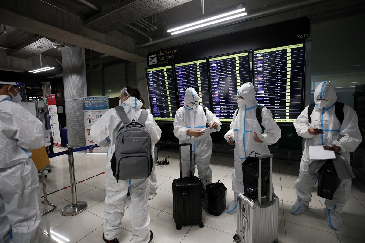 Ķīnas tūristi, kas tērpušies aizsargkostīmos, ieradušies Bangkokas lidostā