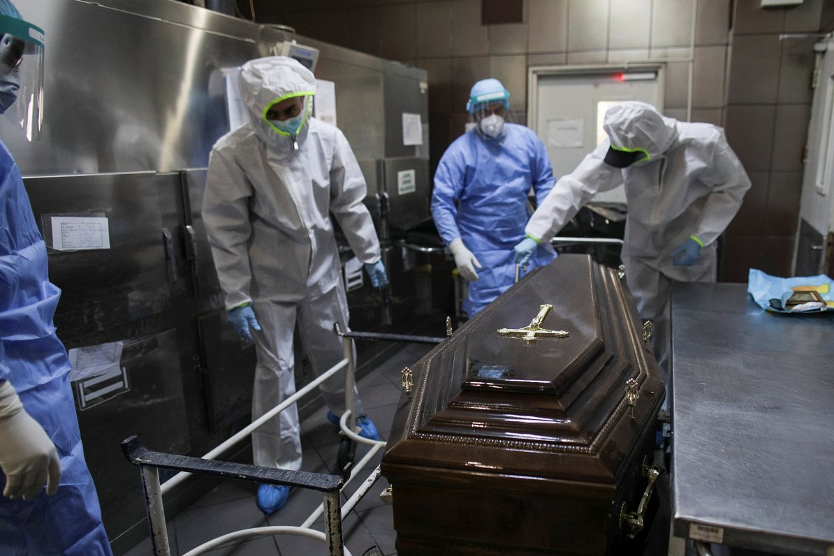Bukarestes klīnikas morgā darbinieki sagatavo ar Covid-19 mirušā nelaiķa zārku transportēšanai uz ka...
