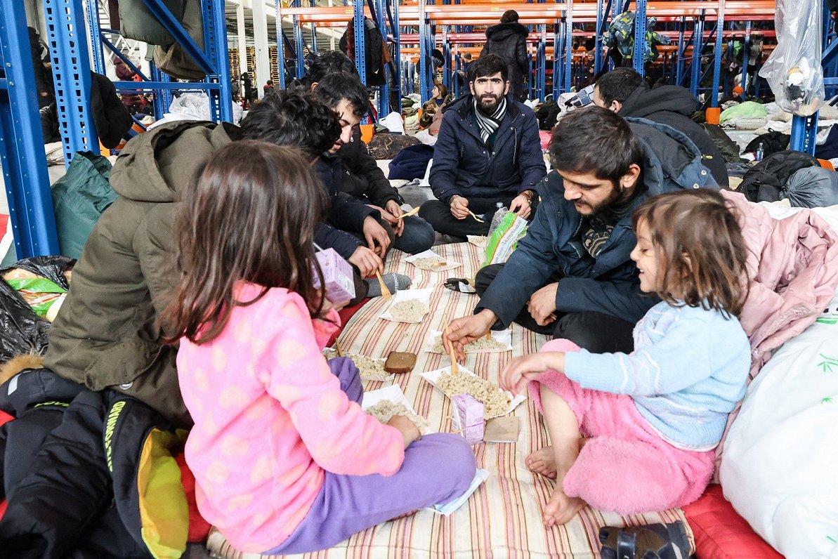 Migrantu ģimene saņem siltu maltīti telpās, kas viņiem ierādītas Baltkrievijas pusē pie Polijas robe...