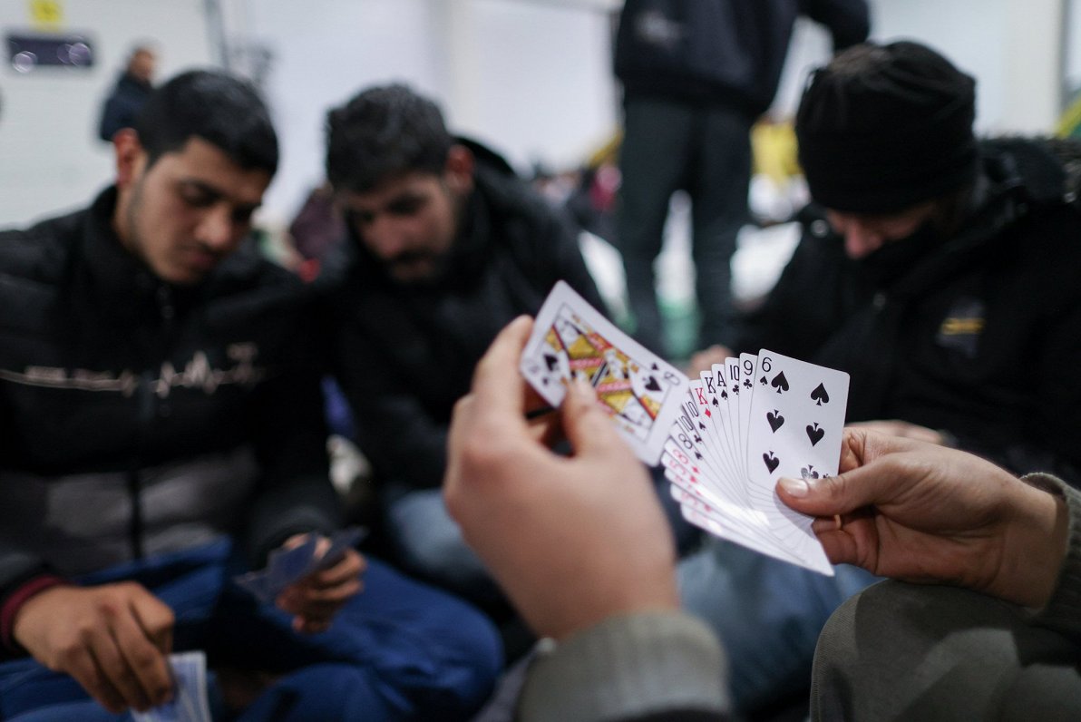 Migranti īsina laiku, spēlējot kārtis loģistikas centrā, kur viņi izmitināti netālu no Baltkrievijas...
