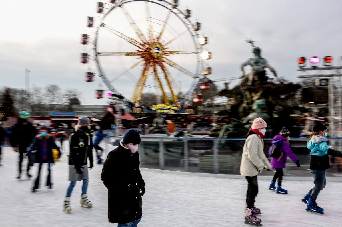 Berlīnē cilvēki ar sejas maskām slido pilsētas centrā