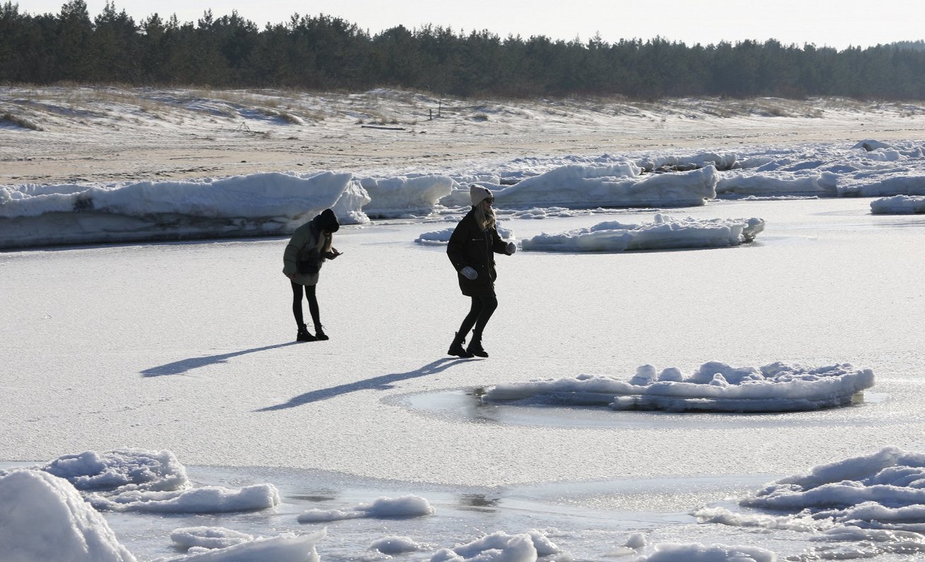 Cilvēki uz ledus Carnikavas pludmalē ziemā.
