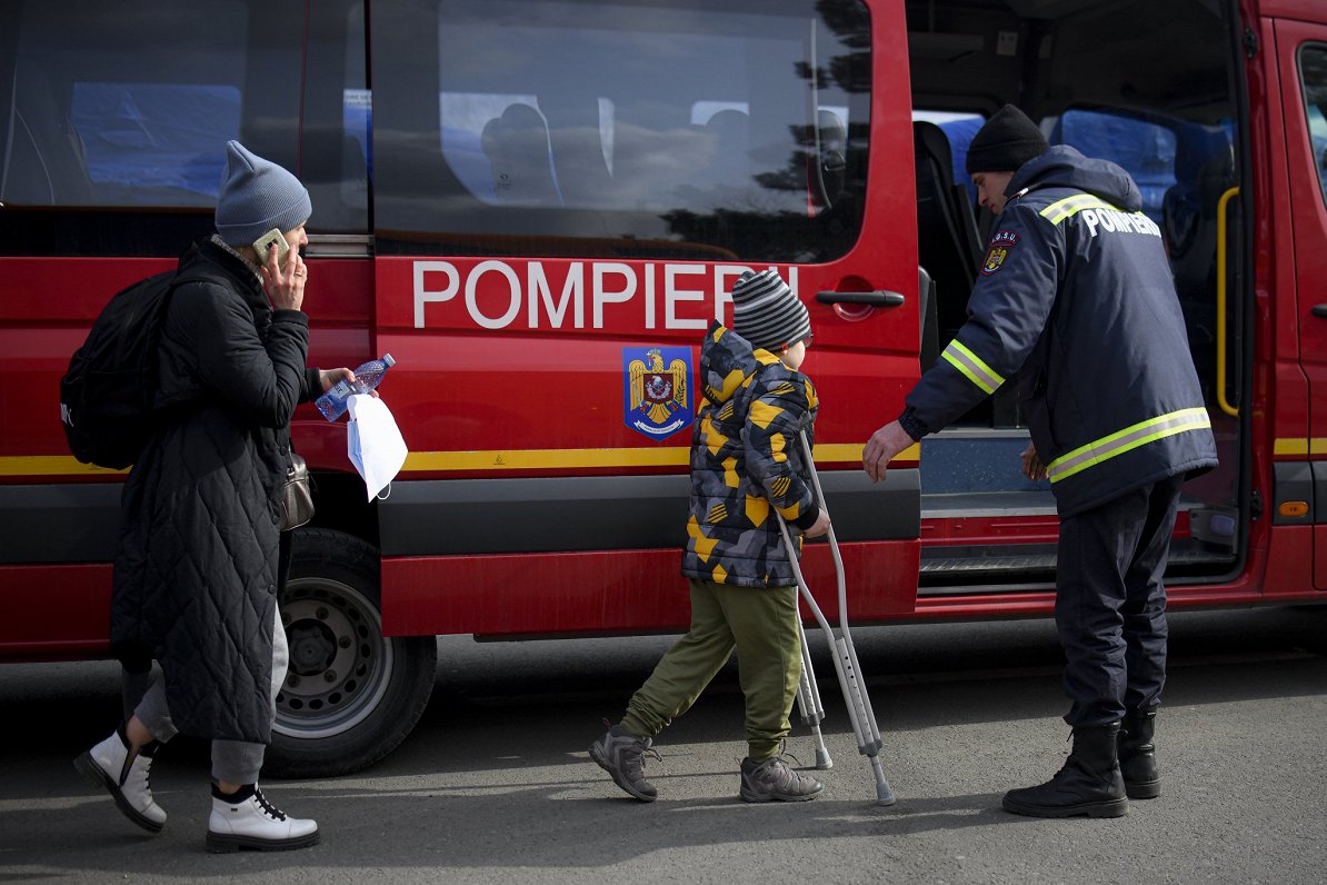 A firefighter helps a refugee fleeing the conflict from neighbouring Ukraine in Siret, Romania, Satu...