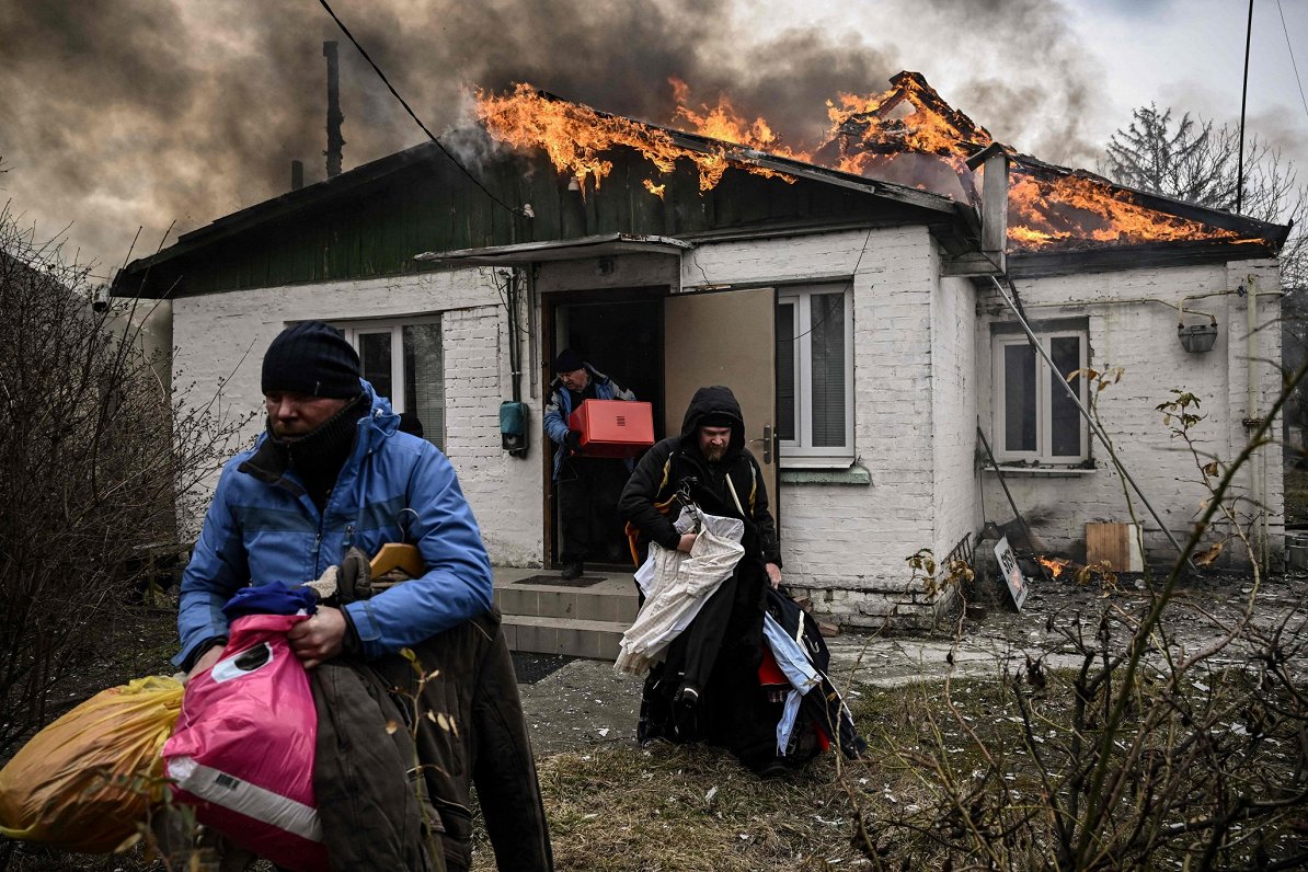 Kijevas apgabala pilsētā Irpiņā iedzīvotāji mēģina glābt savas mantas no degošas mājas, kas cietusi...