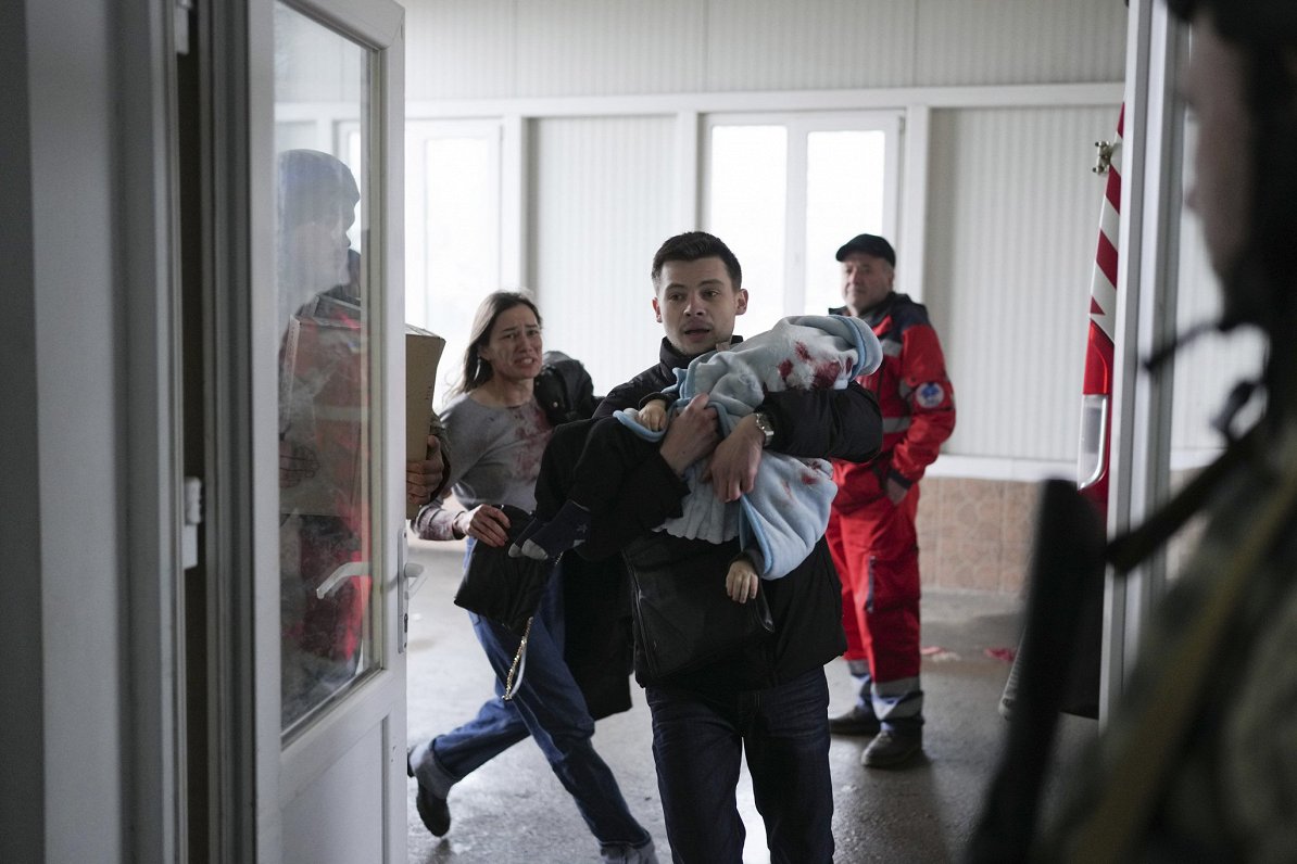 Отец несет раненного осколком полуторагодовалого мальчика. Мать бежит сзади. Украина, Мариуполь, 04....