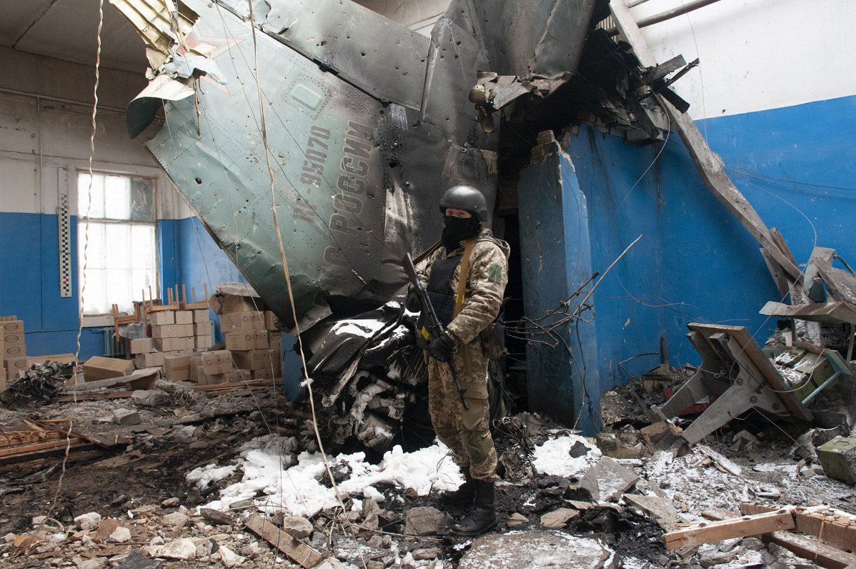 Ukrainas armijas karavīrs pie Krievijas kara lidmašīnas atlūzām daudzdzīvokļu namā Harkivas pilsētā