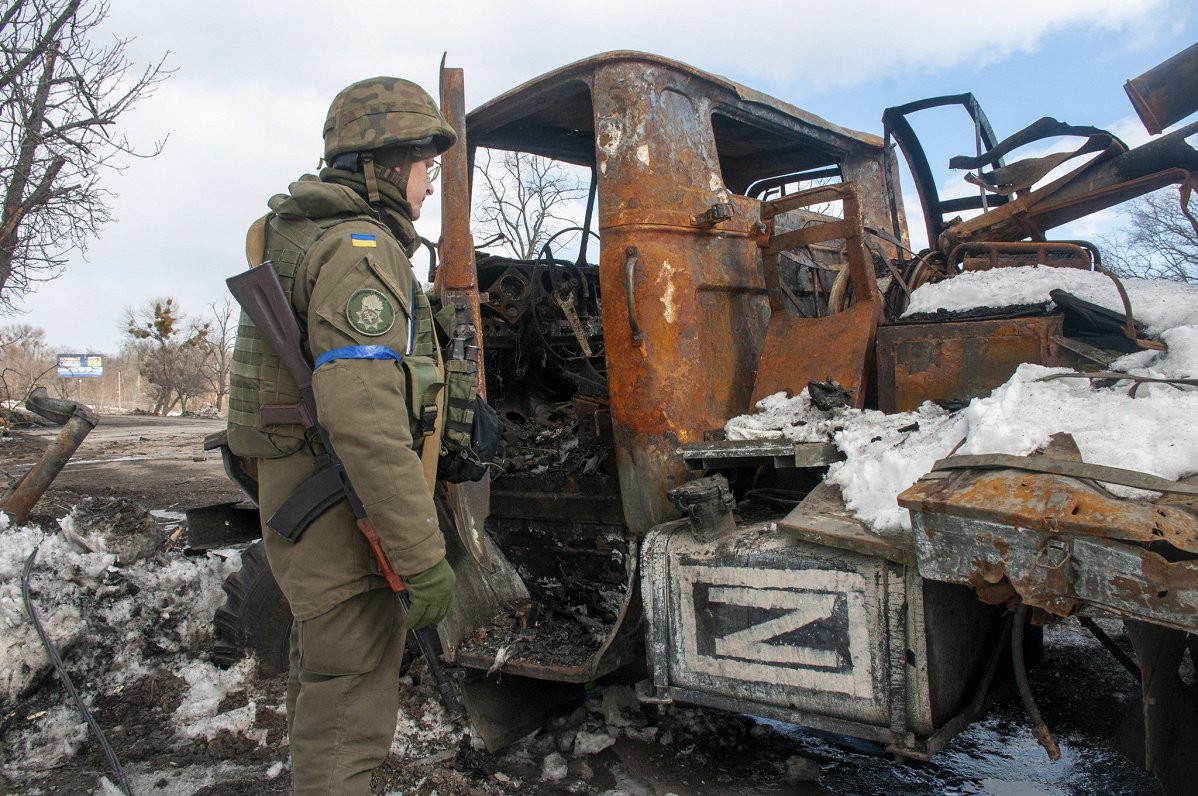 Ukrainas karavīrs pie iznīcinātas Krievijas okupācijas spēku automašīnas