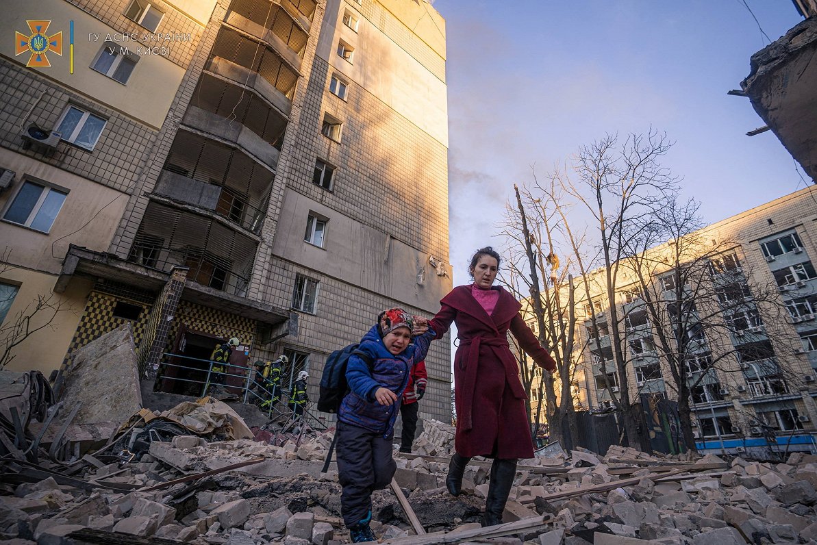 Kijivā sieviete un bērns evakuējas no lādiņa skartās ēkas, 2022.gada marts.