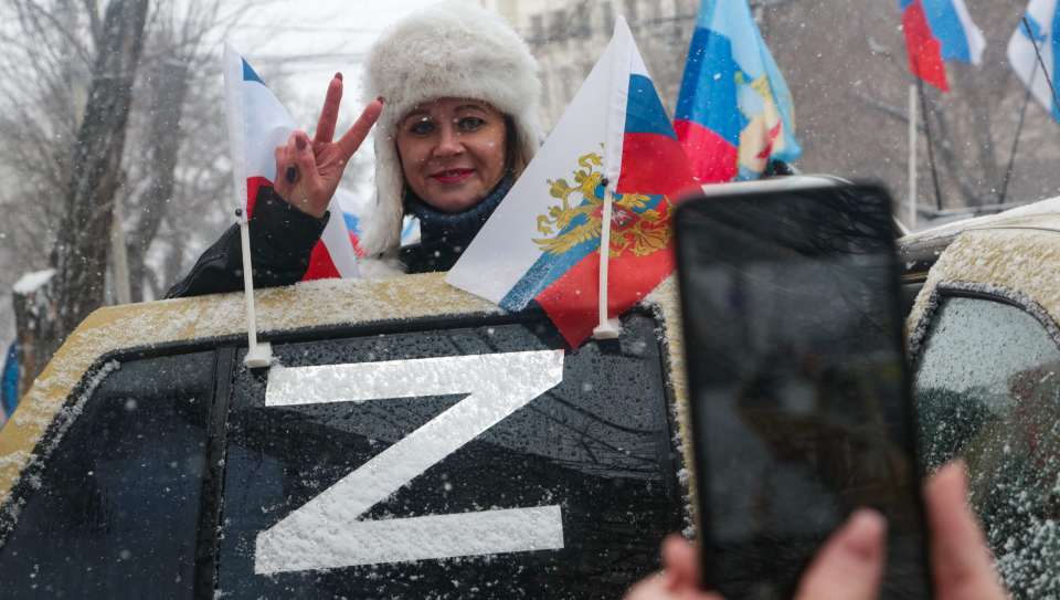 Sieviete pozē pie krievu okupācijas simboliem Simferopolē.