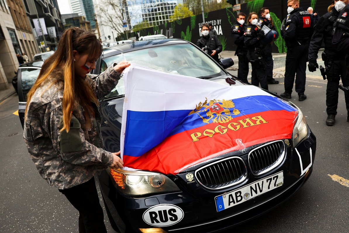 Vācijas pilsētā Frankfurtē prokrieviskā aktīviste ar Krievijas karogu un vācu automašīnu